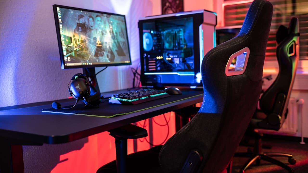 A gaming chair at a home office desk setup with monitors and RGB lighting