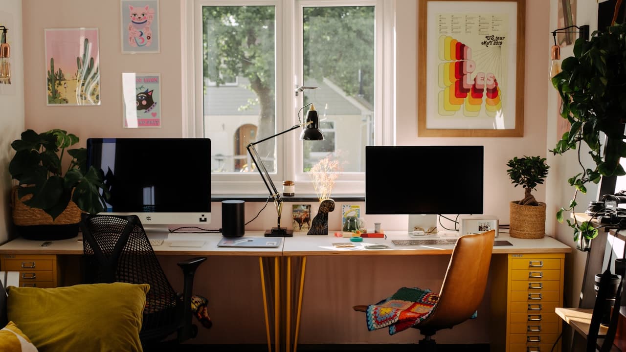 A clean L-shaped corner desk setup in a modern home office with dual monitors