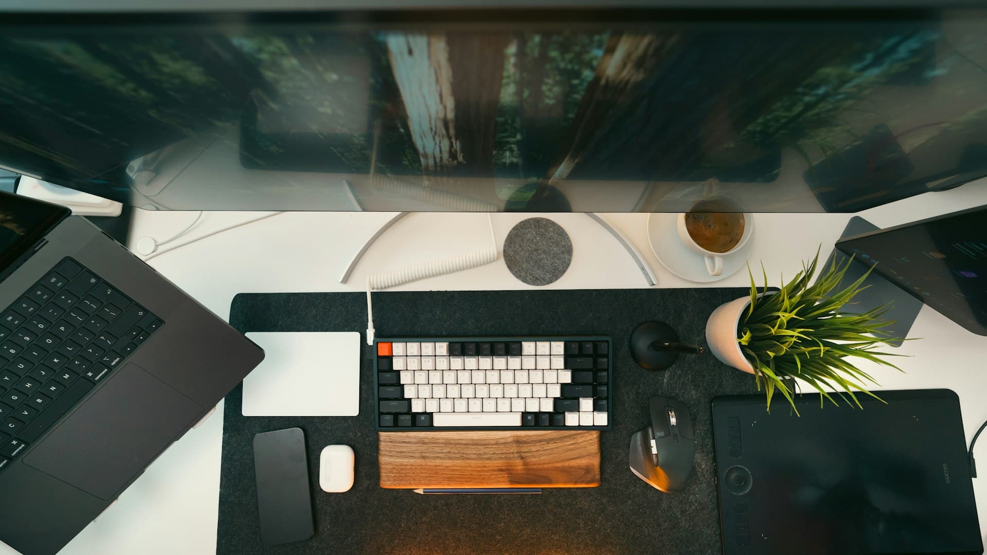 A portable USB-C monitor propped on a desk beside a laptop in a minimal home office setup.